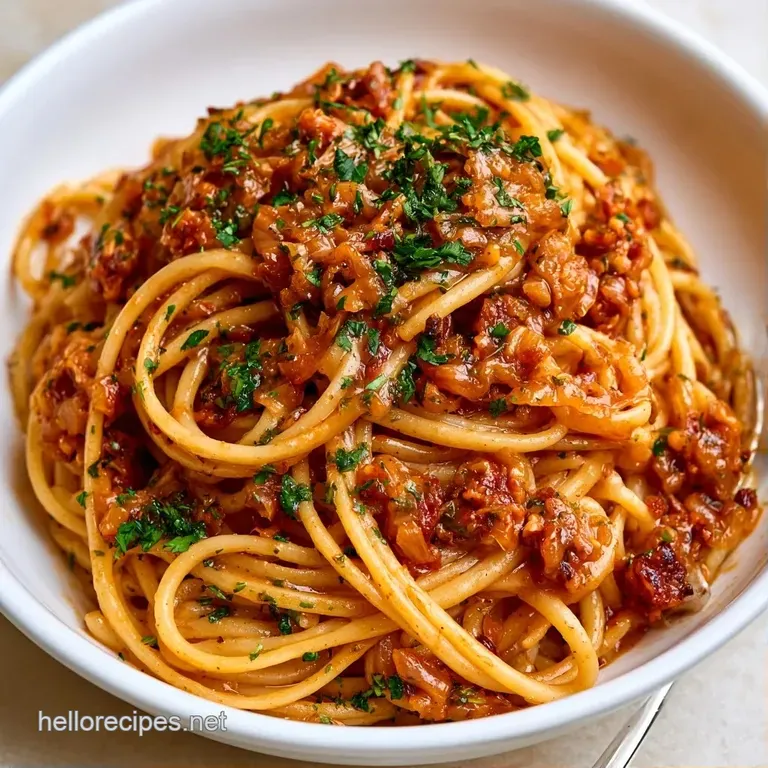 Swirled noodles topped with rich, amber-colored onions and a sprig of thyme on a matte white porcelain plate.